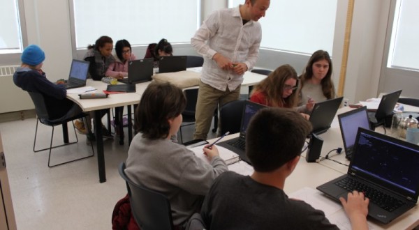 YMCA Academy teacher supervising students working on laptops