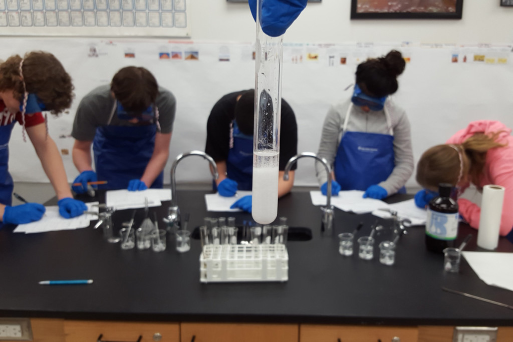 Grade 12 YMCA Academy Chemistry students observe a reaction and record analysis.