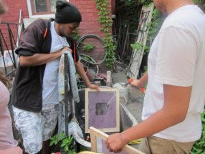 YMCA Academy fashion class students, with Kingi Carpenter, use a silk screening process to design shirts and other materials.