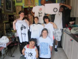 YMCA Academy fashion class students, with Kingi Carpenter, use a silk screening process to design shirts and other materials.