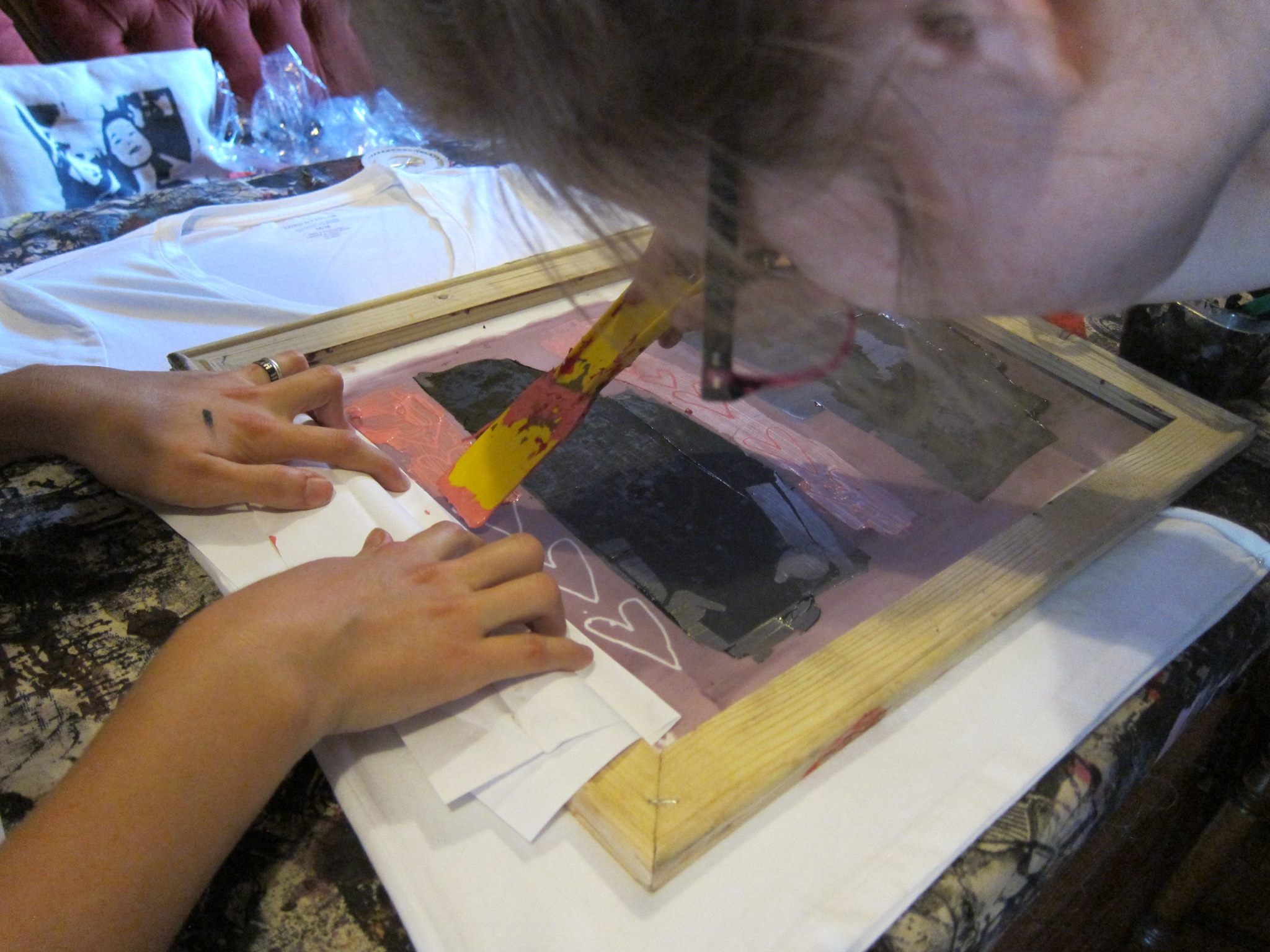 YMCA Academy fashion class students, with Kingi Carpenter, use a silk screening process to design shirts and other materials.