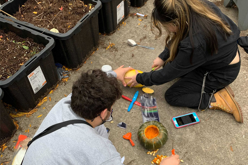 YMCA Academy students carve pumpkins for Halloween