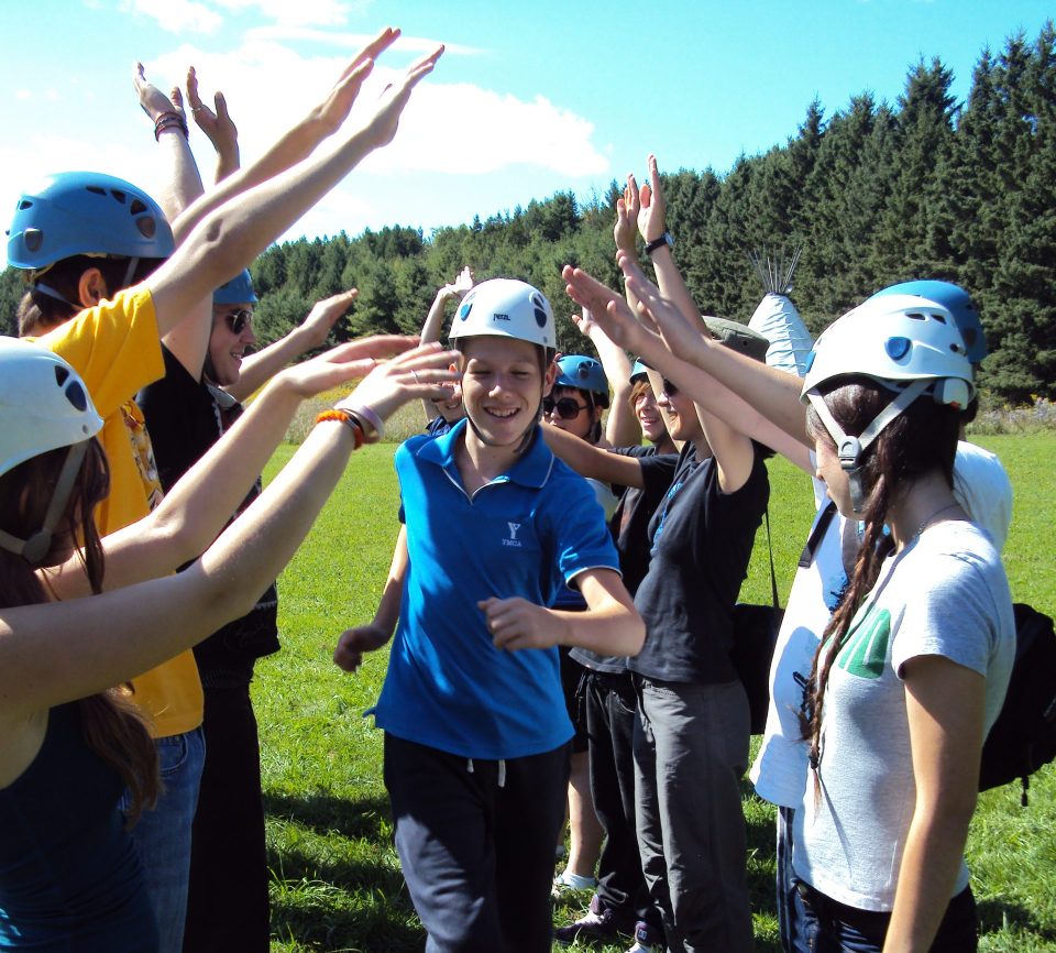 Students wearing helmets participating in outdoor team-building activity at YMCA Academy.