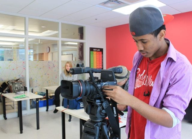 Young student filming with a professional camera at YMCA Academy.