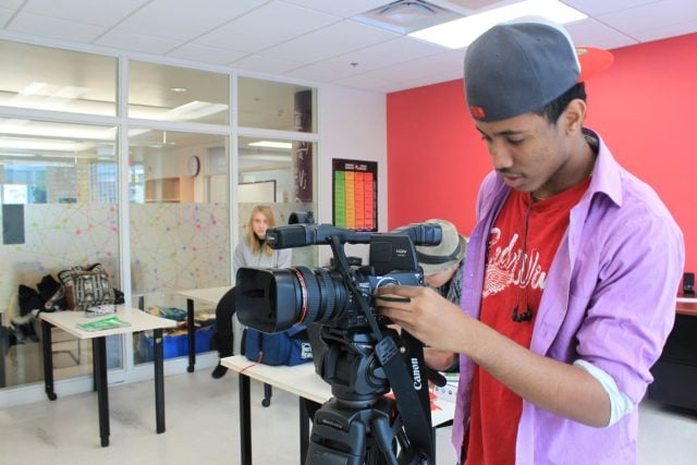 Young student filming with a professional camera at YMCA Academy.