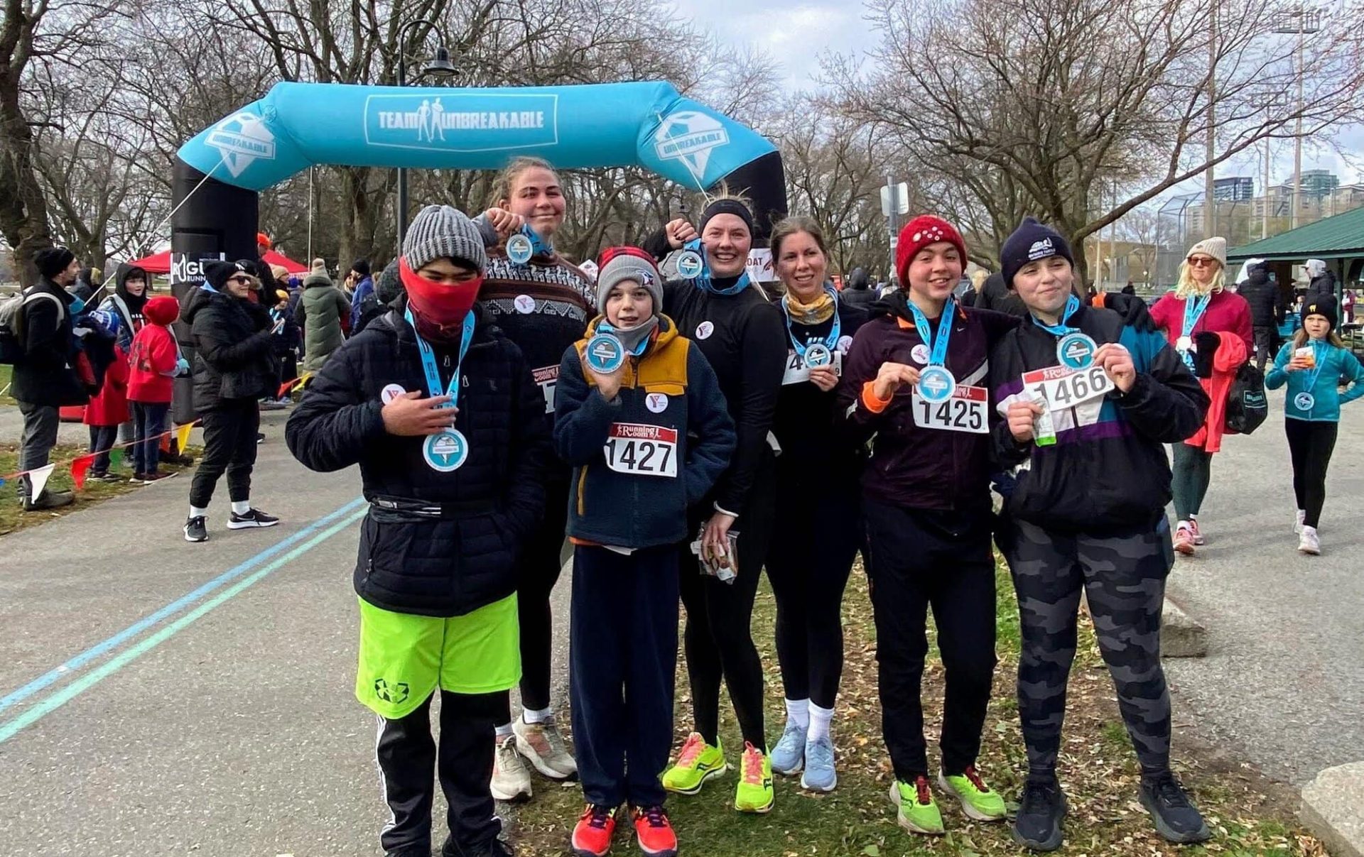 Group of young runners with medals at YMCA Academy event.