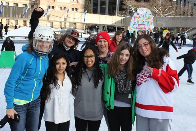 Group of students ice skating at YMCA Academy outdoor rink.