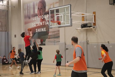 Children playing basketball at YMCA Academy indoor gym.