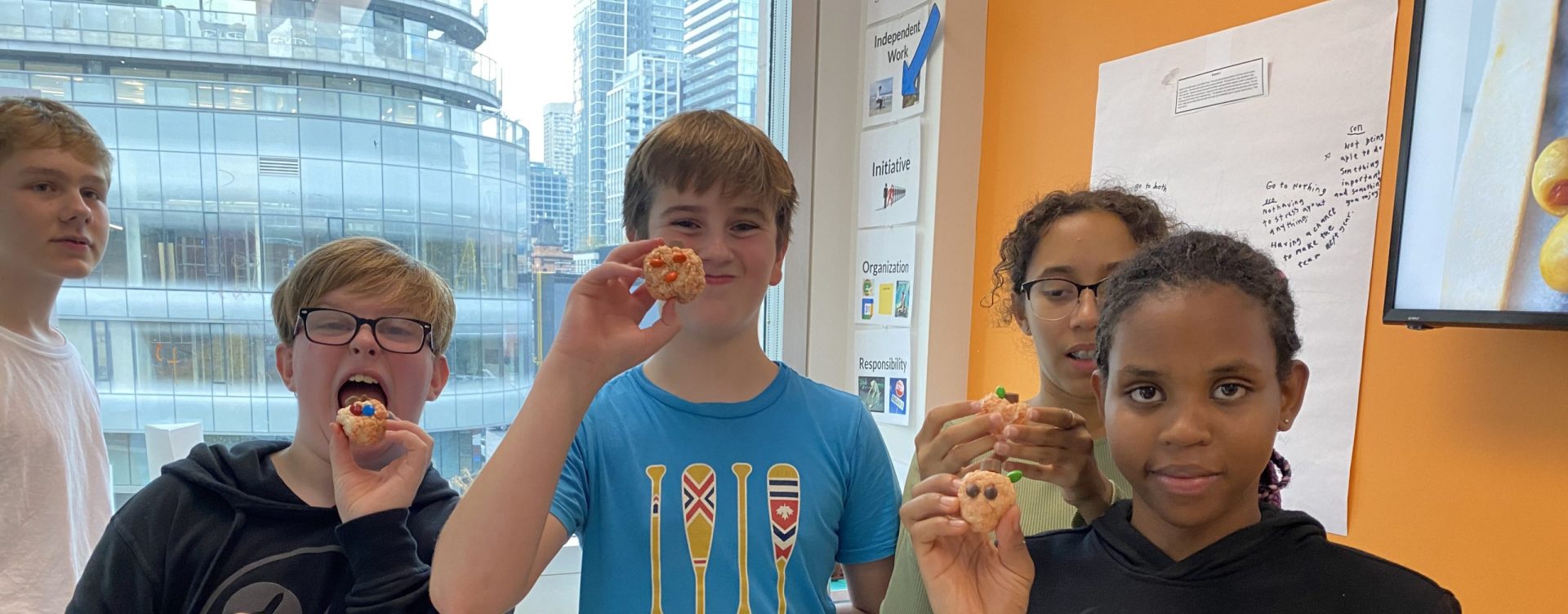 Diverse group of students at YMCA Academy eating snacks and smiling.