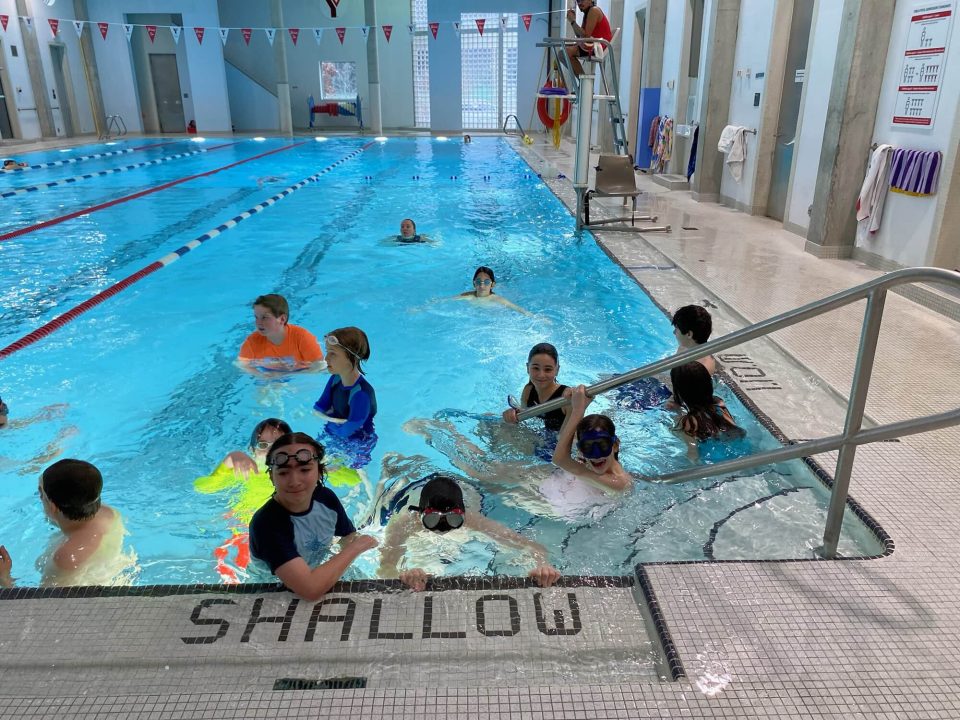 Children enjoying swimming lessons at YMCA Academy indoor pool.