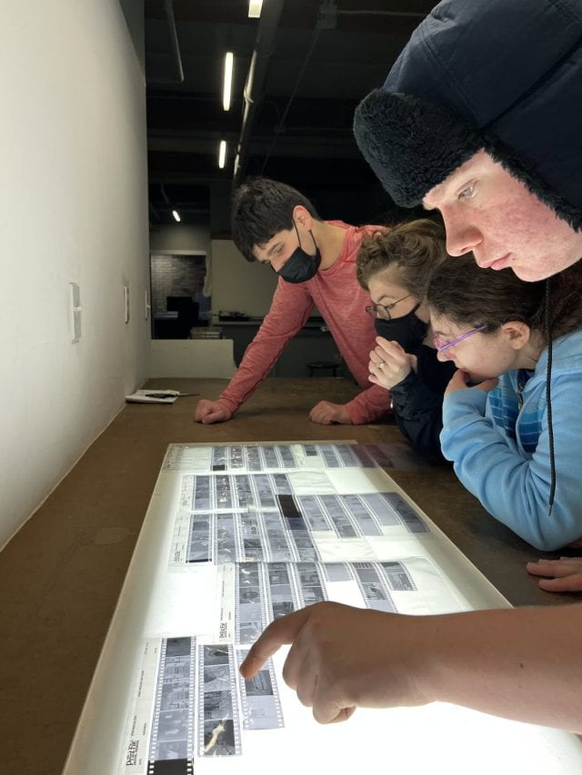 Group of students studying digital images on a table at YMCA Academy.