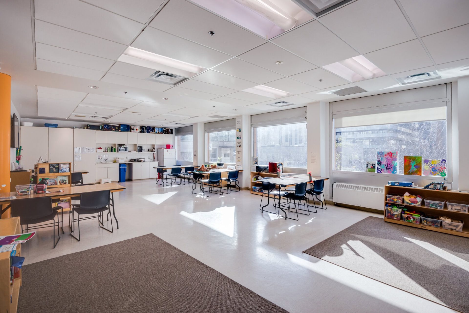 Bright YMCA Academy classroom with tables, chairs, and large windows.