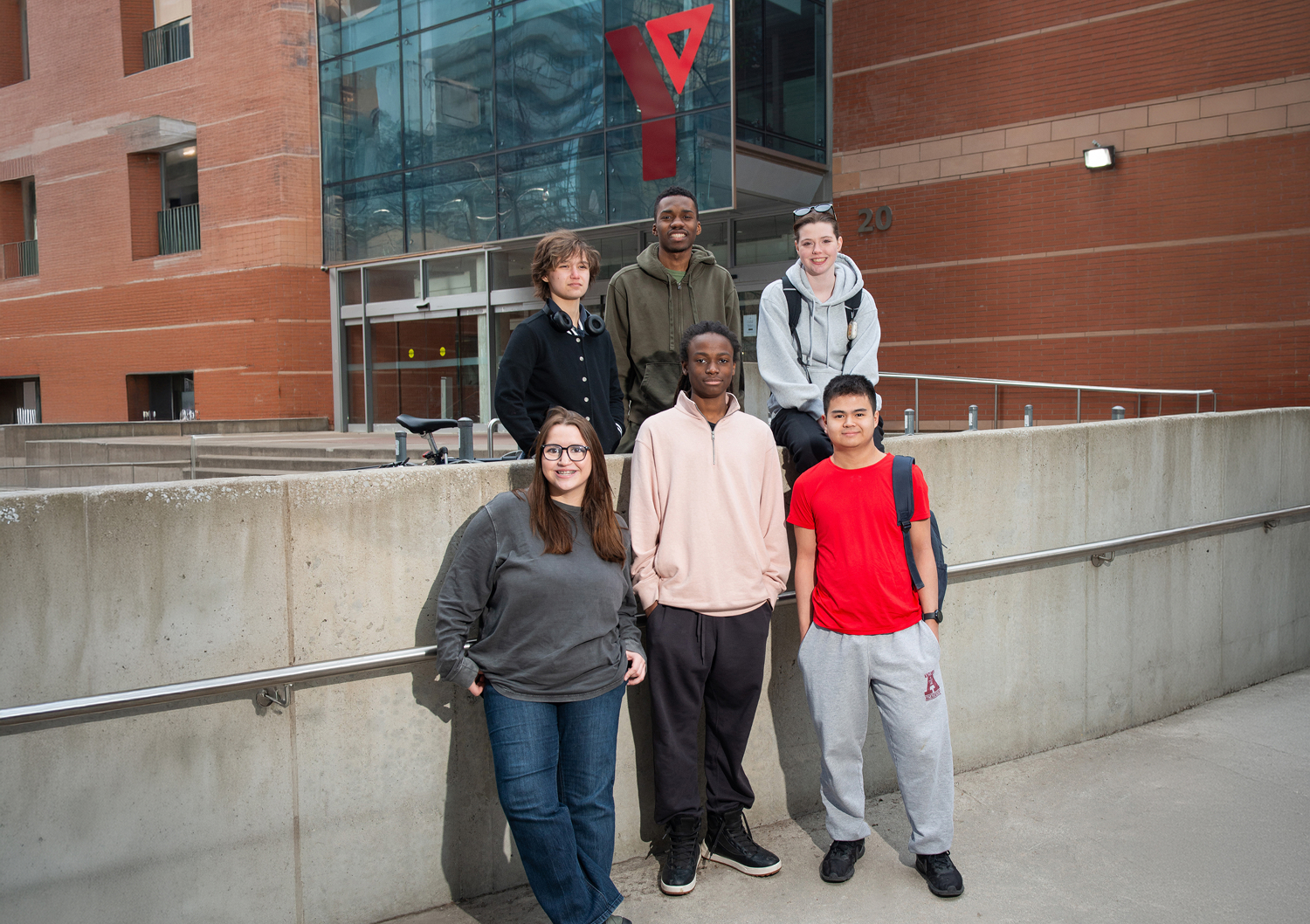 Diverse group of students outside YMCA Academy building in casual attire.